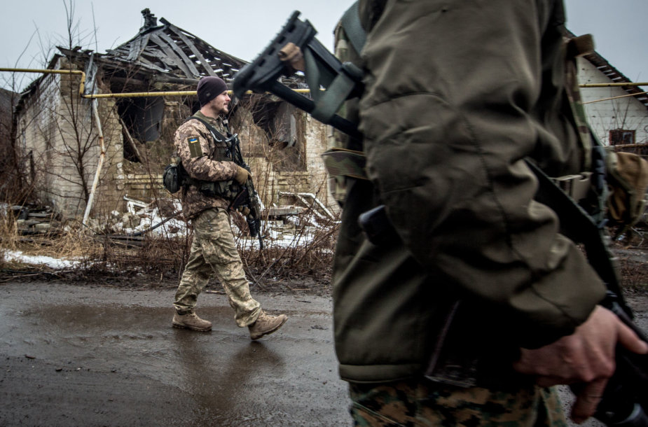 Ukrainos kariai eina pro sugriautus namus