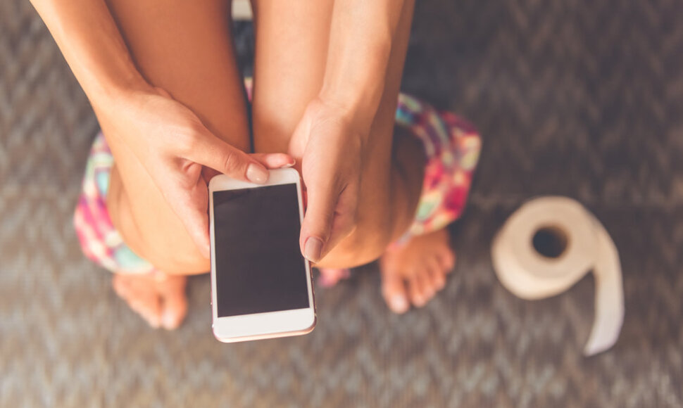 Moteris tualete su telefonu