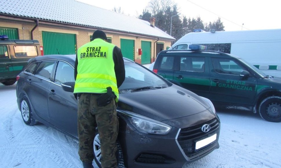 Lenkijos pareigūnas prie vogto automobilio.