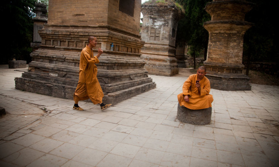 Mobiliaisiais telefonais turistus fotografuojantys Šaolino vienuolyno vienuoliai
