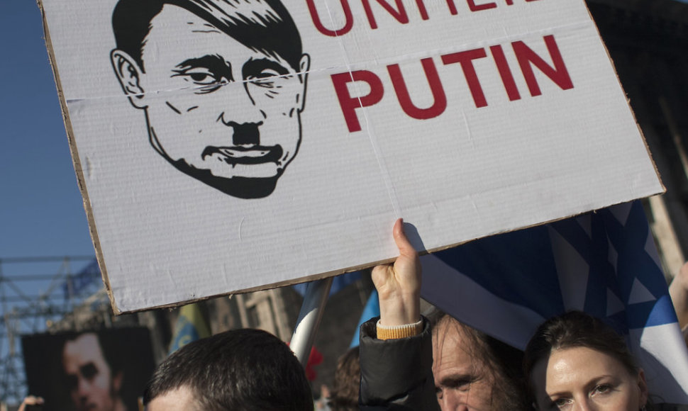 A woman holds a sign depicting Russian President Vladimir Putin as Adolf Hitler as she attends a rally at Independence Square in Kiev March 9, 2014. Russian forces tightened their grip on Crimea on Sunday despite a U.S. warning to Moscow that annexing the southern Ukrainian region would close the do