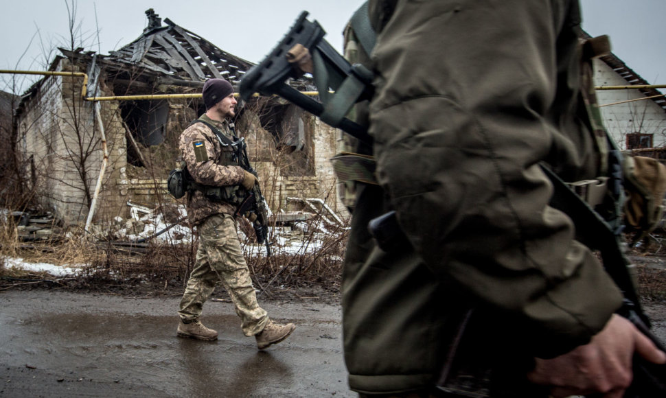 Ukrainos kariai eina pro sugriautus namus