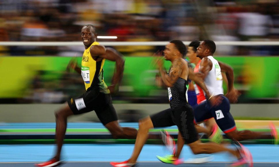 Usainas Boltas olimpinių žaidynių bėgimo rungtyje žvilgteli į nuo jo atsiliekančius varžovus
