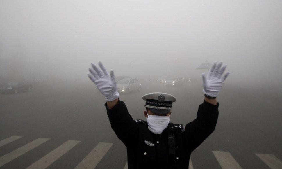 Policininkas per smogą bando reguliuoti eismą sankryžoje.