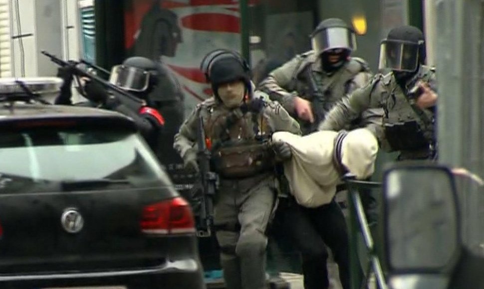 Belgijos policininkai veda penktadienį sulaikytą asmenį.
