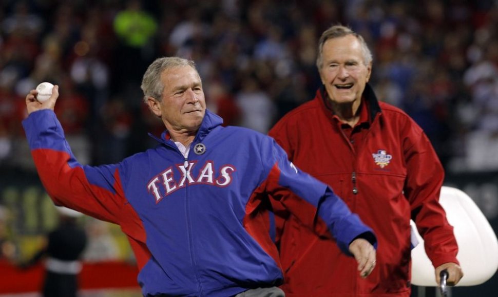 George'as Bushas vyresnysis (dešinėje) žiūri kaip jo sūnus George'as Bushas meta beisbolo kamuolį.