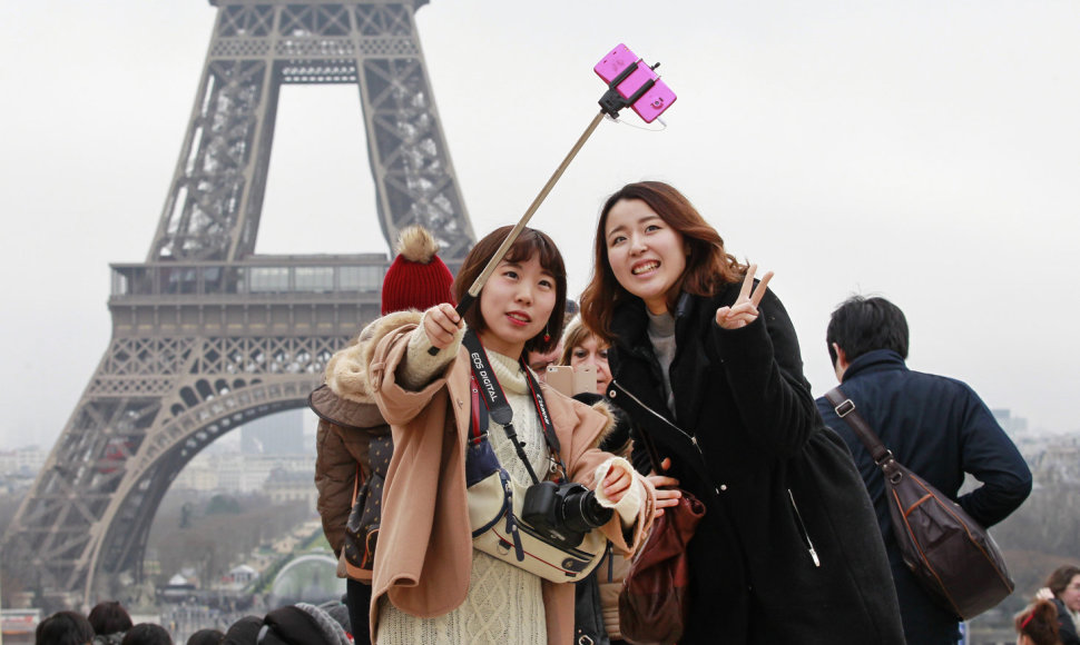 Turistės darosi asmenukę Paryžiuje prie Eifelio bokšto