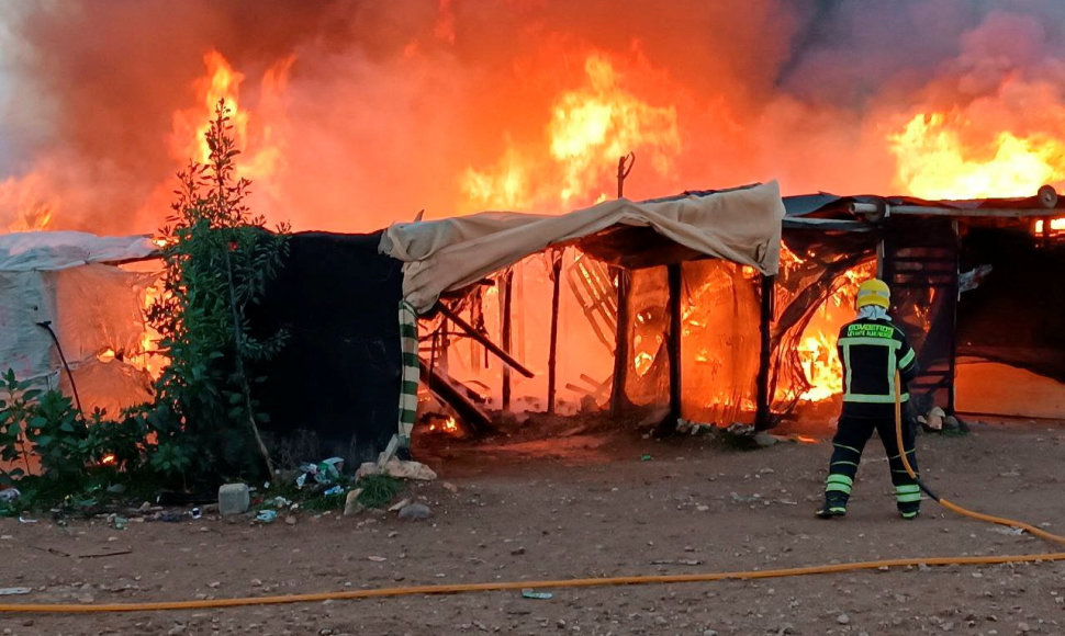 Ugniagesys bando užgesinti gaisrą  El Valilio migrantų stovykloje