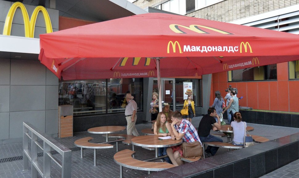 Maskvoje žmonės sėdi prie uždaryto „McDonald's“ restorano stalų.