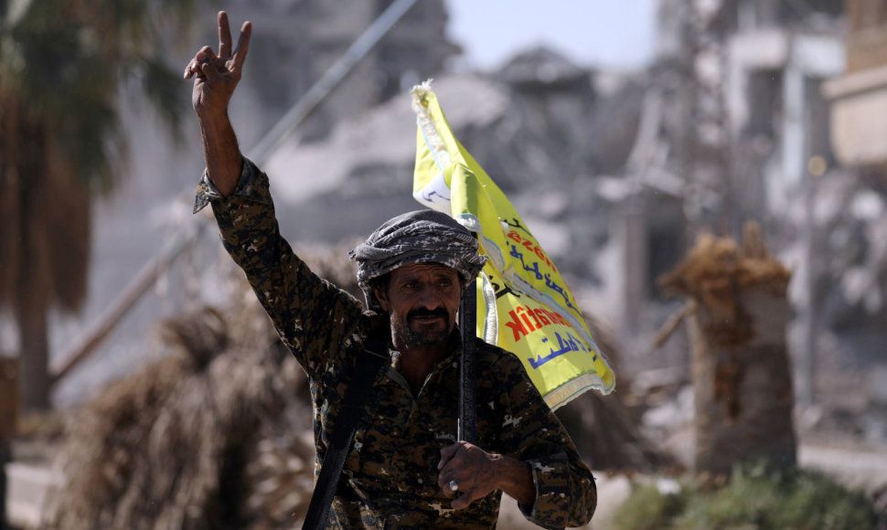 Sirijos pajėgų karys rodo pergalės ženklą buvusioje IS sostinėje Rakoje
