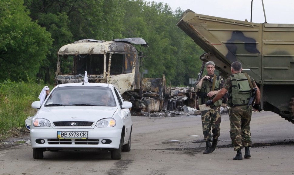 Vyrai su baltais skudurėliais atomobiliu važiuoja pro separatistų patikrinimo postą Luhanske