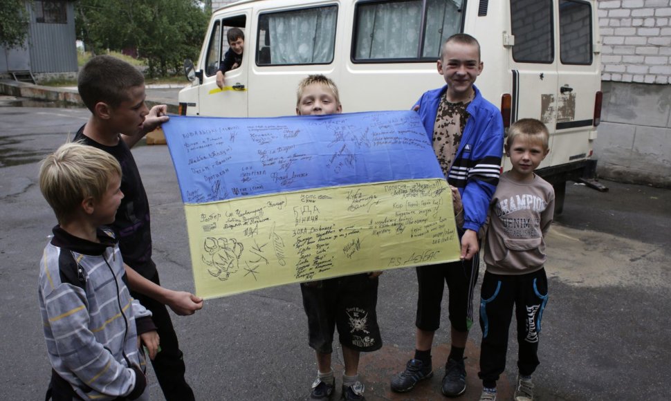 Vaikai rodo Ukrainos vėliavą su savanorių karių parašais