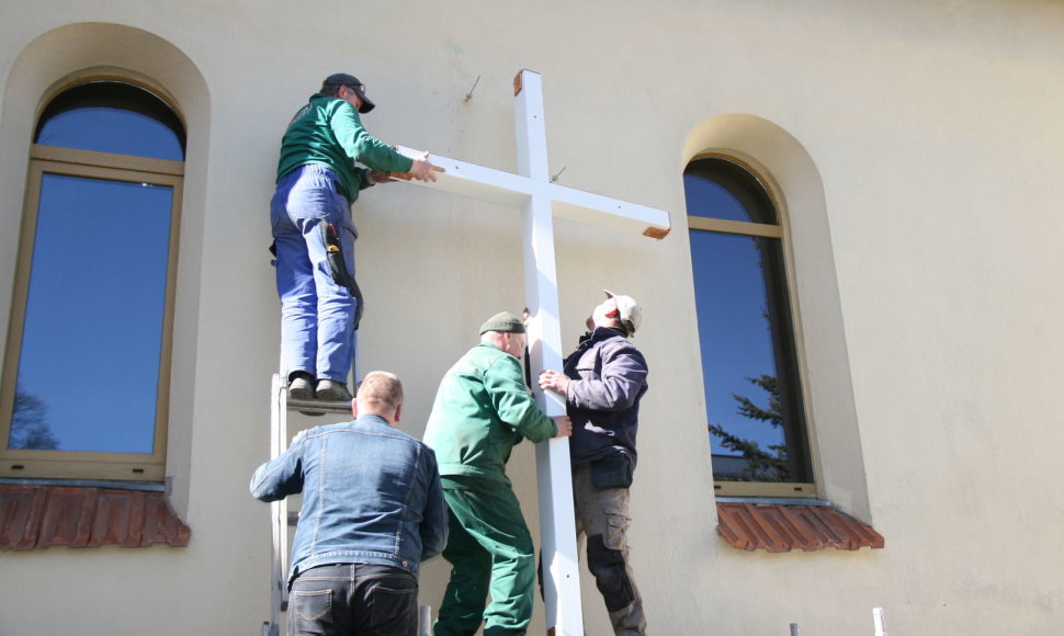 Prie bažnyčios tvirtinamas kryžius