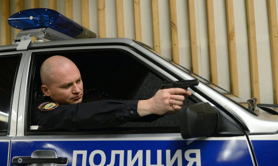 Rusijos policininkas automobilyje su ginklu