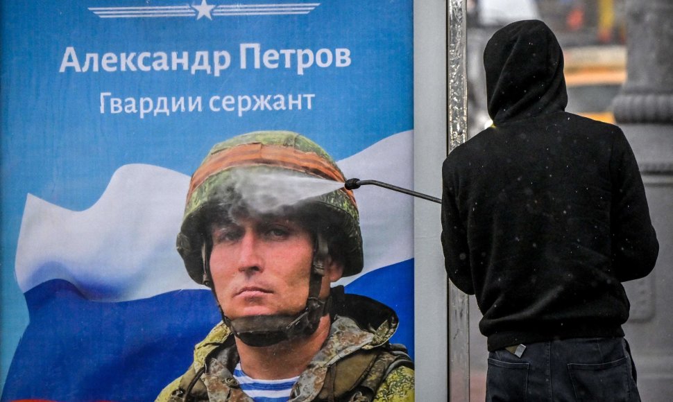 Maskvoje valomas propagandinis plakatas su kariu ir užrašu „Šlovė Rusijos didvyriams“