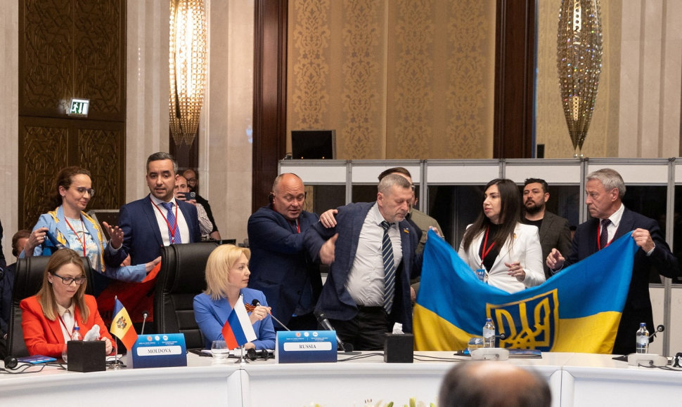 Ukrainos delegacijos nariai išskleidžia savo šalies vėliavą šalia Rusijos delegacijos vadovės pavaduotojos Olgos Timofejevos