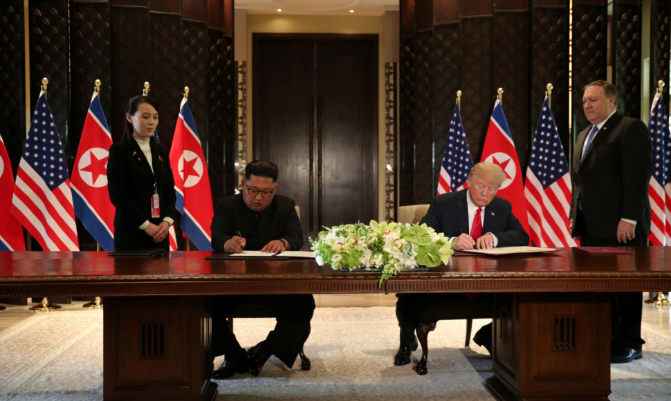 Kim Jong Unas ir Donaldas Trumpas pasirašo dokumentą