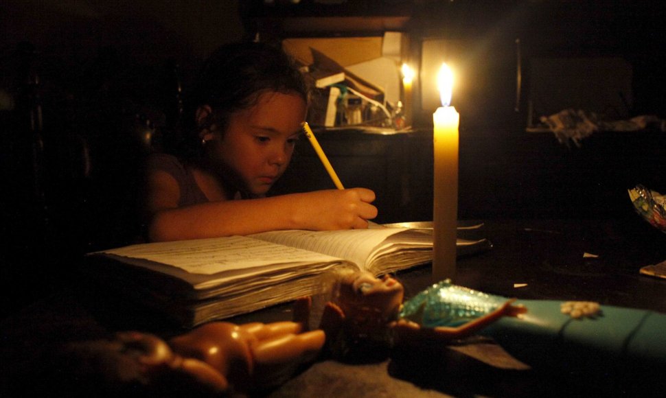 Venesuela taupo elektros energiją, dėl to ji tiekiama ribotą laiką. Mergaitė ruošia namų darbus prie žvakių šviesos.