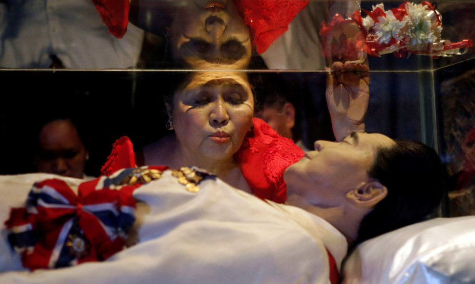 Imelda Marcos bučiuoja stiklinį velionio vyro karstą.