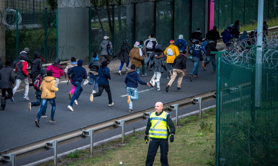 Migrantai bėgantys link Eurotunelio Prancūzijoje nekreipia dėmesio į policininką