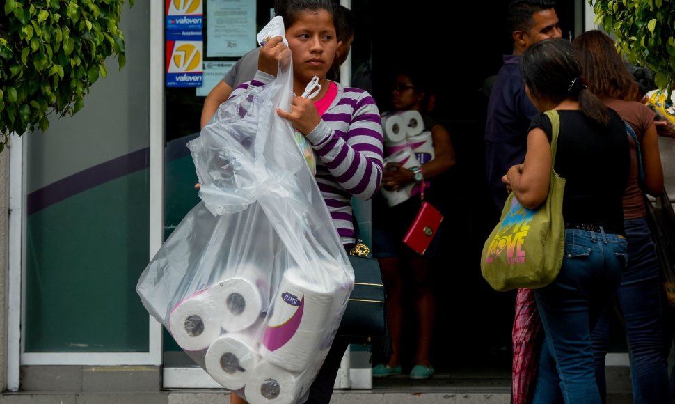 Tualetinį popierių iš parduotuvės nešanti moteris Karakase