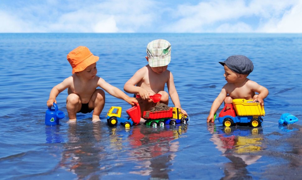 Trys berniukai žaidžia paplūdimyje