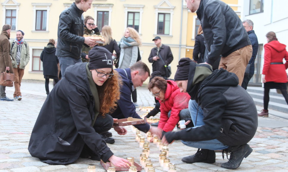 Protesto akcijos dalyviai Teatro aikštėje iš gedulo žvakučių išdėliojo kryžiaus ženklą.