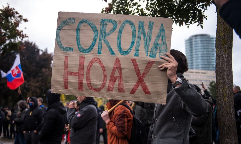 Protestuotojas Slovakijoje laiko plakatą su užrašu „korona apgaulė“