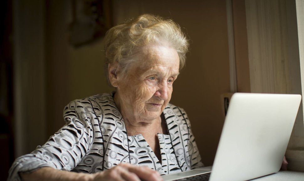 Garbaus amžiaus moteris prie kompiuterio