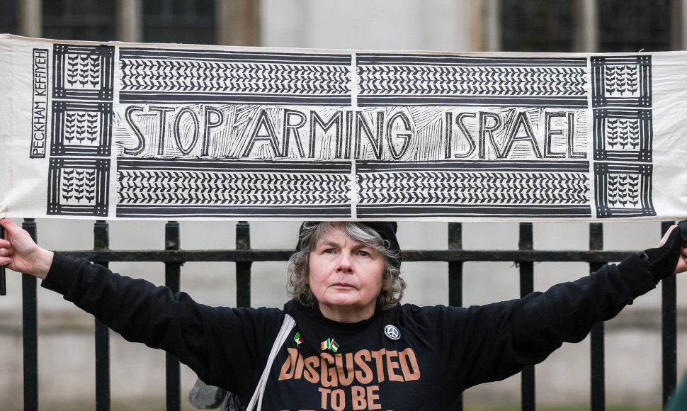 Palestiną palaikanti moteris laiko plakatą: „Nustokite ginkluoti Izraelį“