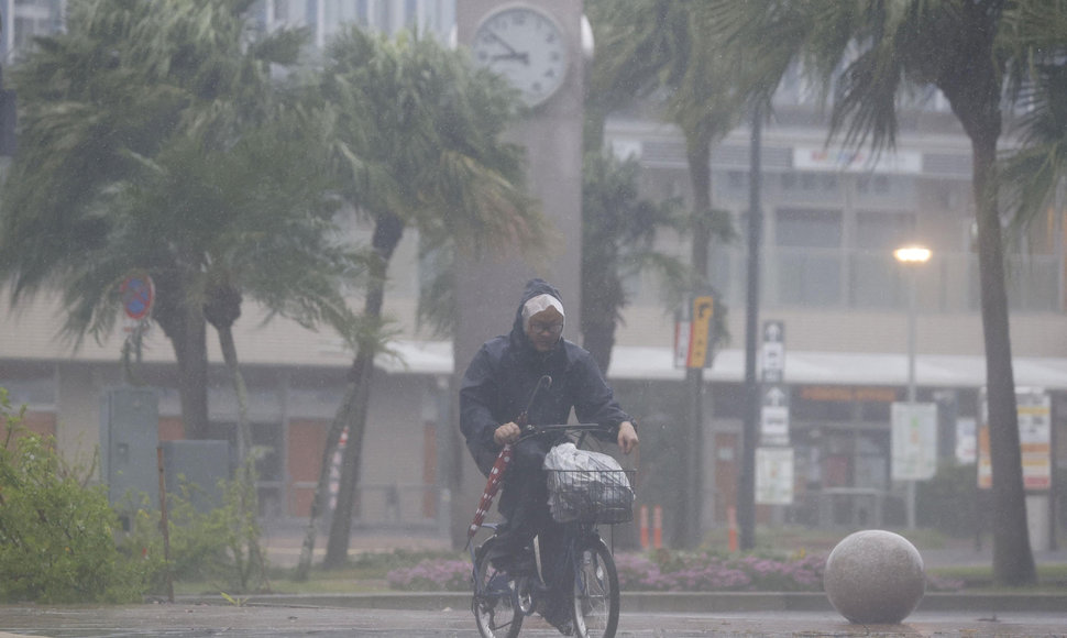 Vyras Mijazakyje važiuoja dviračiu per smarkų lietų ir vėją, kurį sukėlė taifūnas Nanmadolis