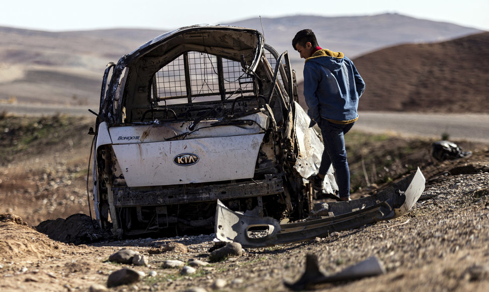 Vyras apžiūri Turkijos paleistos raketos suniokotą automobilį