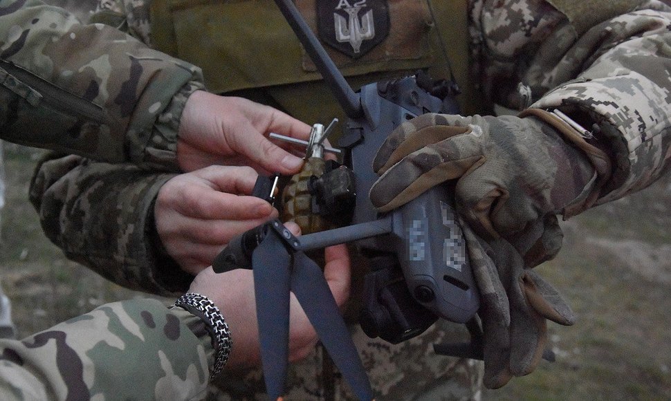 Ukrainian soldiers attach explosives to a drone