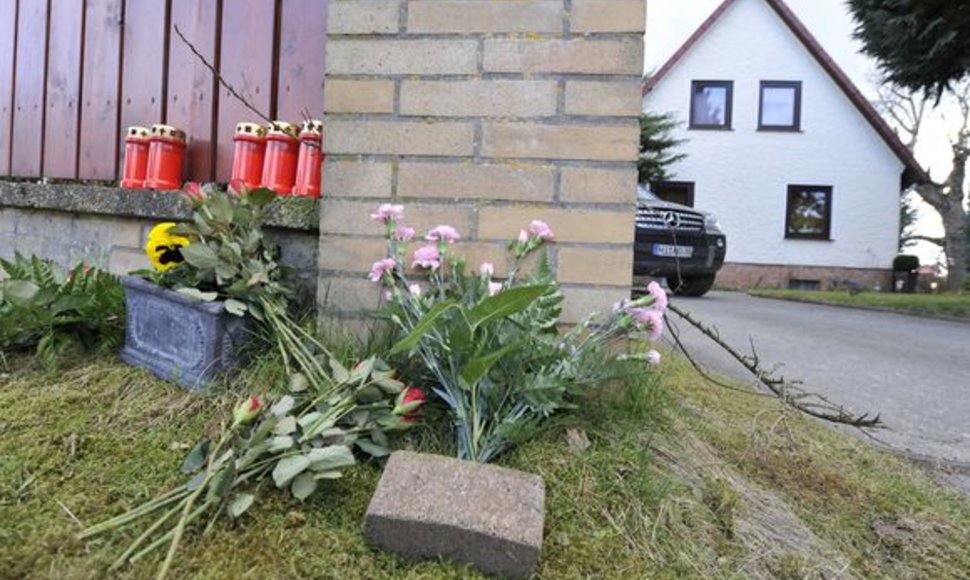 Gėlės ir žvakės padėtos šalia namo.
