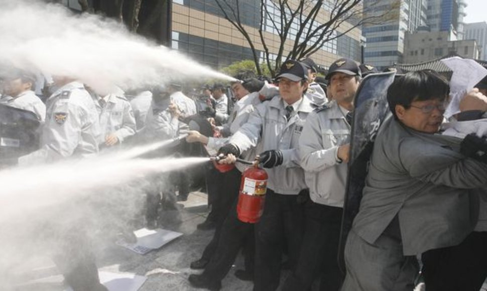Policininkai gesina demonstrantų padegtas Š.Korėjos simbolius.