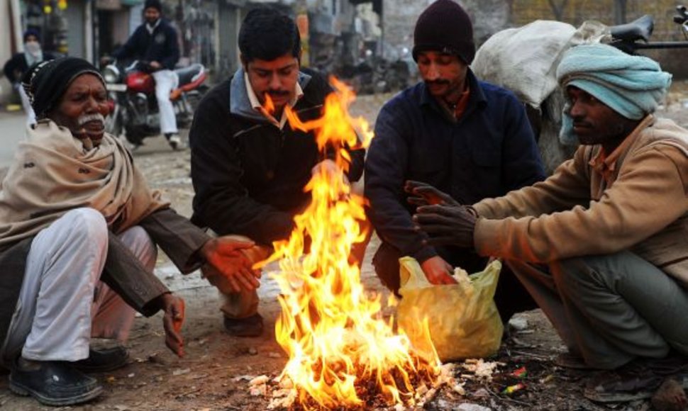 Indijos darbininkai šildosi prie ugnies