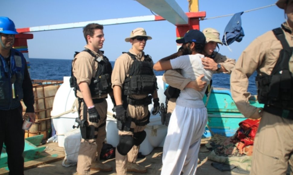 JAV jūreivis iš laivo „Kidd“ sveikinasi su iraniečiu, išgelbėtu iš piratų nelaisvės.