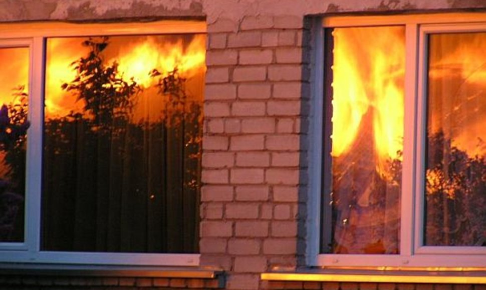 Liepsnos atspindžiai gretimų namų languose.