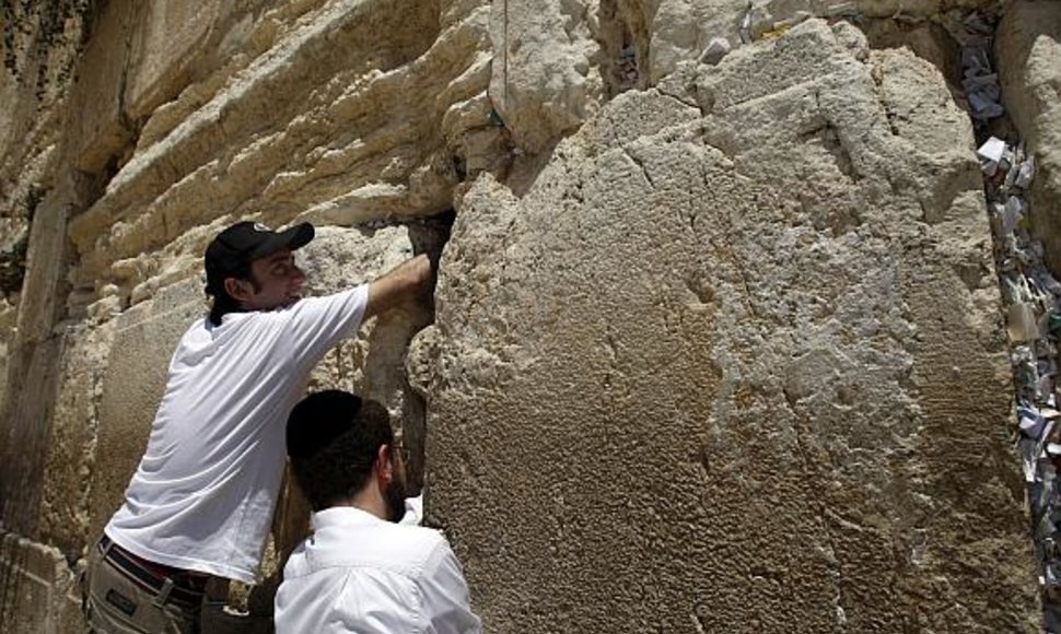 Alonas Niras (kairėje) kiša ritinėlius su maldomis į Raudų sienos plyšį
