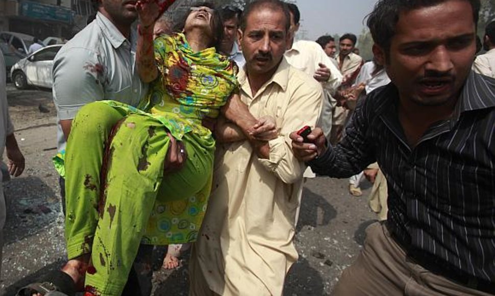 Žmonės iš sprogimo vietos išneša sužeistą moterį