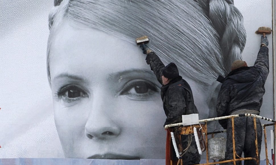 Darbininkai prieš rinkimų savaitgalį uždengia kandidatės Julijos Tymošenko agitacinį plakatą.