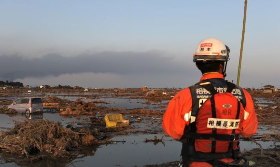 Gelbėtojas stovi cunamio nusiaubtoje teritorijoje, kurioje kažkada buvo Sendajaus miesto dalis.