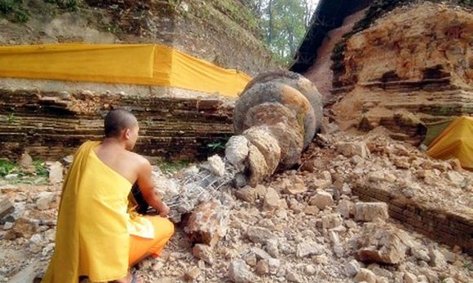 Mianmaro pasienyje Tailando budistų vienuolis sėdi prie sugriautos šventyklos.