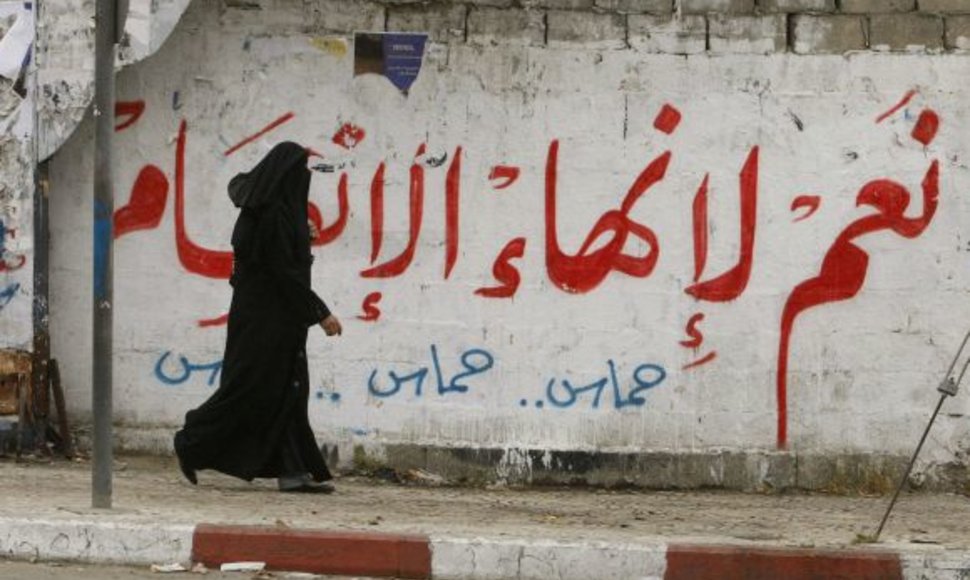 Palestinietė Gazos mieste eina pro užrašą ant sienos „Taip pasidalijimo pabaigai“.