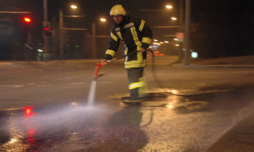 Ugniagesys avarijos vietoje plauna asfaltą