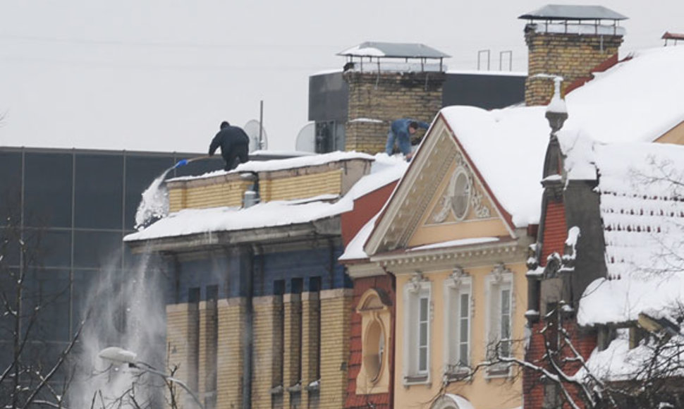 Du vyrai nuo stogo kasa sniegą