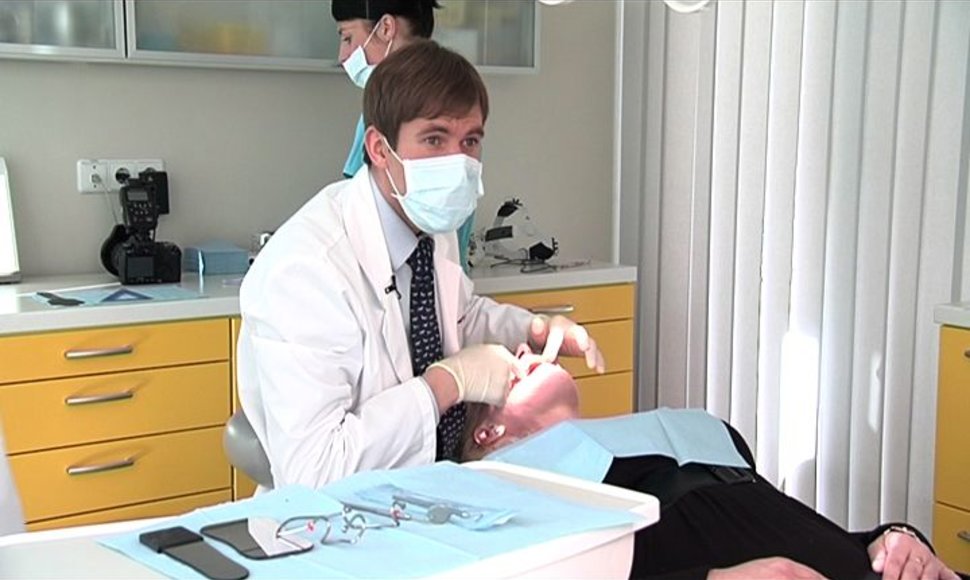 Gydytojas periodontologas apžiūri dantis.