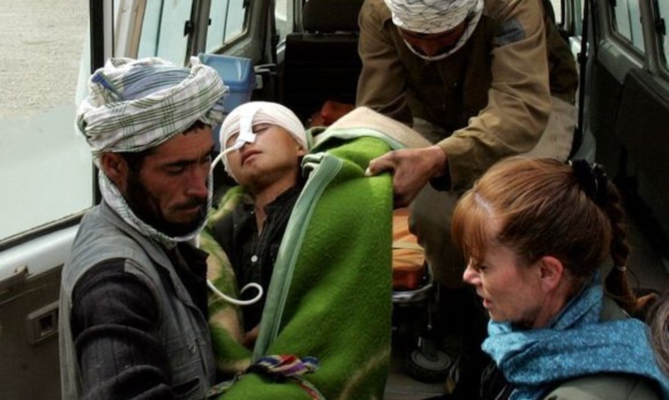Sunkiai sužalotas afganistaniečių berniuką tėvas neša į sreigtasparnį.