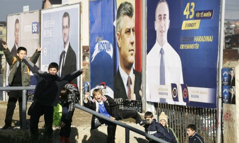 Vaikai pozuoja prie Kosove vykstančių rinkimų plakatų.