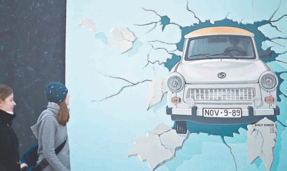 Turistai ir praeiviai tyrinėja meno kūrinius ant atrestauruotos 1,3 km ilgio sienos ruožo, vadinamo Rytų galerija – sieną pramuša VDR simboliu tapęs automobilis „Trabant“.